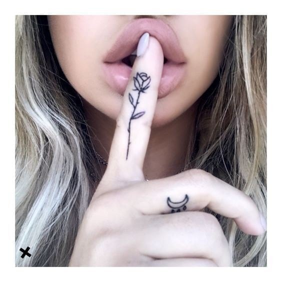 Tattoos auf den Fingern: kleine Rose am Zeigefinger und Mond am Mittelfinger