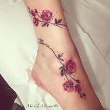 Tatuagens no tornozelo da mulher ao redor do tornozelo e ramos do pé com flores vermelhas