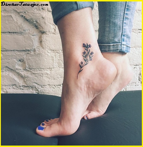 Tatuagens nos galhos pretos da mulher do tornozelo