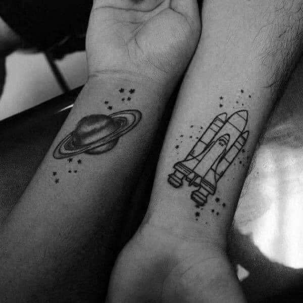 Tattoos, die Sie mit Ihrem Liebsten erhalten können: Rakete und Saturn auf den Handgelenken des Paares