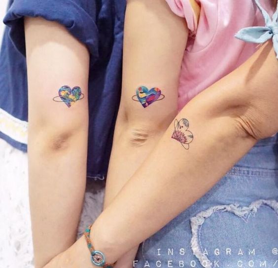 Tatuaggi per tre amici, sorelle, cugini Tre cuori con un cerchio tipo Saturno e colorati sul braccio