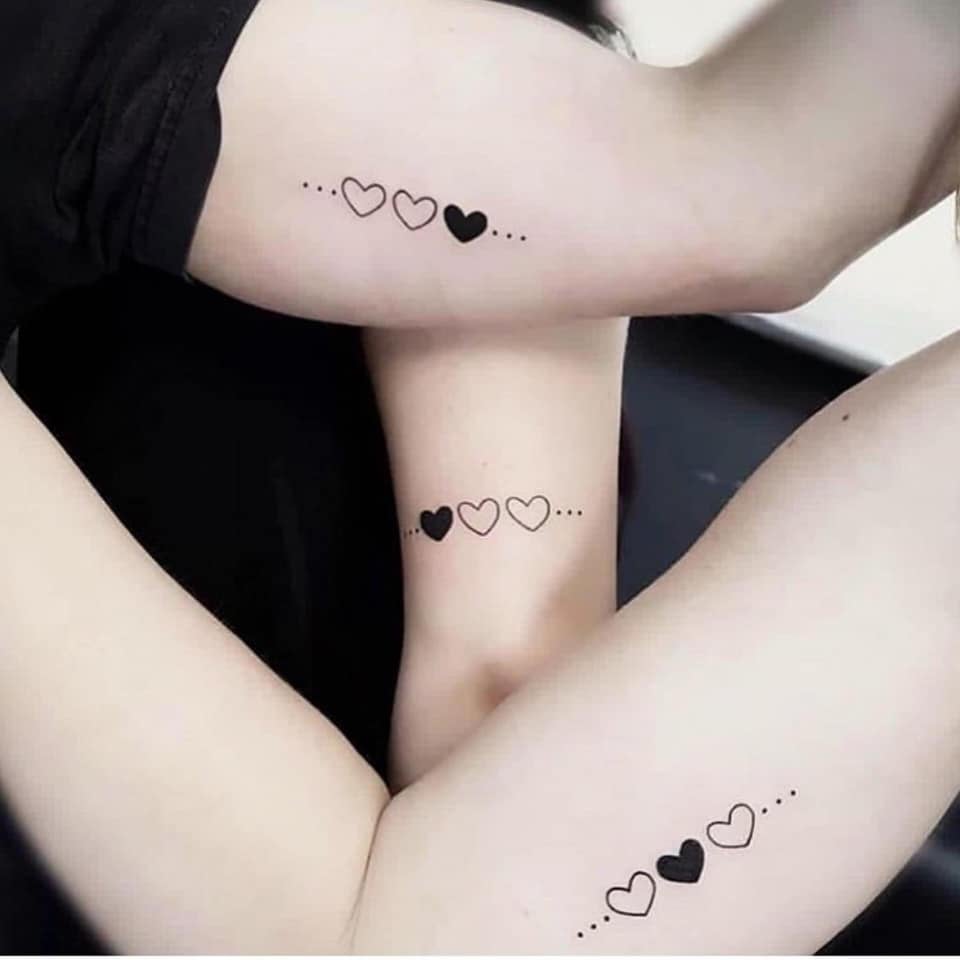 Tattoos für drei Freunde, Schwestern, Cousins. Drei Herzen, eines schwarz an einer anderen Stelle auf jeder Schwester mit drei Punkten auf dem Arm