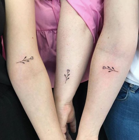 Tattoos for Three Friends Sisters Cousins three small flowers with stem on forearm
