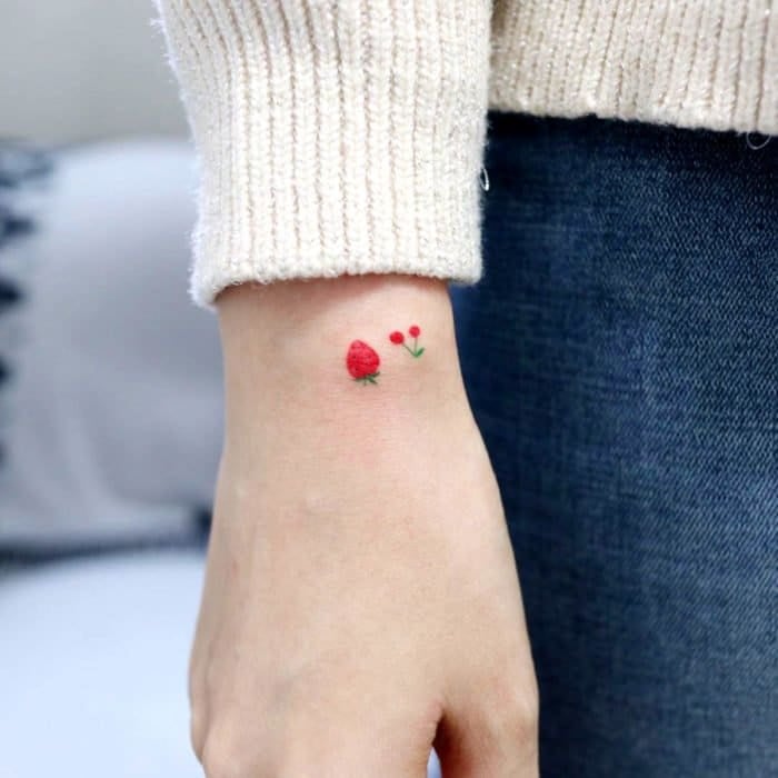 Tatuajes super pequenos para mujeres cereza y frutilla rojas en costado de la mano