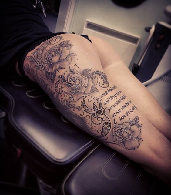 Tattoo of a woman in the leg area with flowers and inscriptions on the thigh and leg