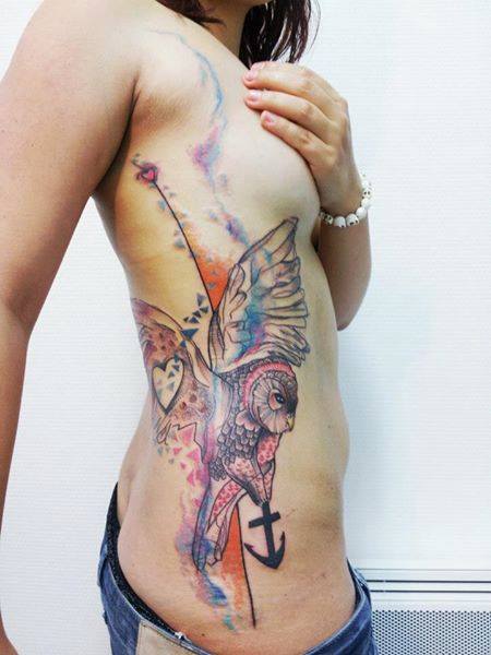 tatuaje en la costilla buho ancla corazon y motivos coloridos en mujer