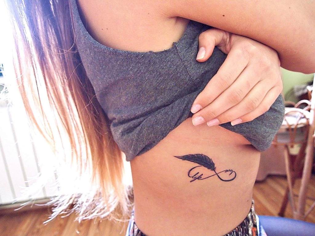 tatuaje en la costilla simbolo de infinito y pluma